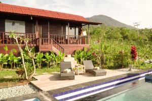 a house with a deck next to a swimming pool at Dukuh Baturan Villa in Jatiluwih