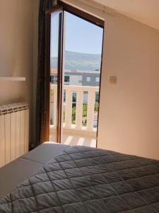ein Schlafzimmer mit Bett und Blick auf einen Balkon in der Unterkunft Galiot Apartman in Ðenovići