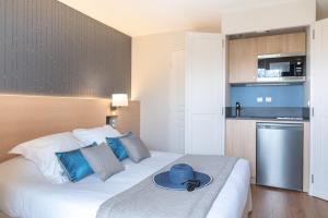 a hotel room with a bed with a hat on it at La Closerie SPA & Résidence Hôtel in Deauville