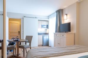 a room with a bed and a table and a television at La Closerie SPA & Résidence Hôtel in Deauville