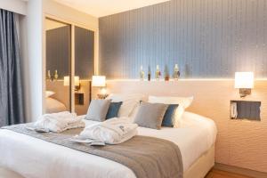 a bedroom with a large bed with towels on it at La Closerie SPA & Résidence Hôtel in Deauville