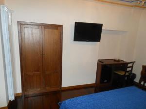 タルクイーニアにあるPalazzo Rosatiの木製のキャビネットと壁掛けテレビ付きのベッドルーム1室