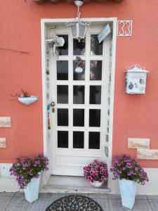 una casa rosa con una porta bianca e due piante in vaso di Da Mamma e Papà Sirolo a Sirolo
