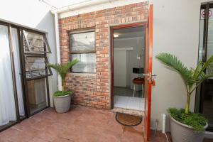an open door to a brick building with two palm trees at Farm View Guest House in East London