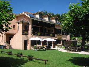 a large building with tables and umbrellas in a yard at Pyrenées Emotions in Malvézie