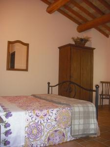 a bedroom with a bed with a dresser and a mirror at Agriturismo Biologico Villa Rosa in Monte Guiduccio