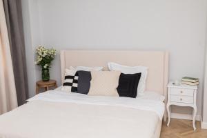 a white bed with black and white pillows on it at Explore the City from Its Center in a Chic Balcony Apartment in Bucharest
