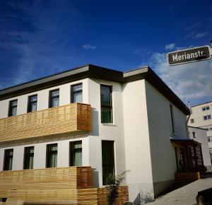 a white building with a balcony and a street sign at Hotel Merian in Friedrichshafen