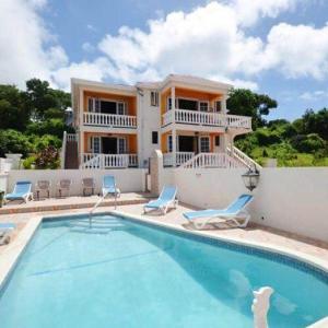 uma casa com piscina em frente a uma casa em Villa Riana Barbados em Christ Church