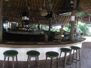 un bar con taburetes verdes en un mostrador en Papillon Garden Bar Villas en Bamburi