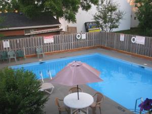 una mesa con sombrilla junto a la piscina en Sunset Inn, en Niagara Falls