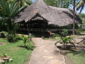 a thatch roofed house with a path leading to it at Papillon Garden Bar Villas in Bamburi