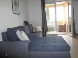a blue couch in a living room with a large window at Apartments Golić in Biograd na Moru