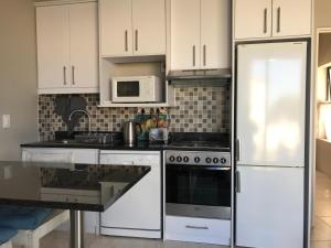 a kitchen with white cabinets and a white refrigerator at Indigo Place - Blue in Hermanus