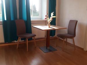 una mesa con dos sillas y un jarrón con flores. en Hartl Apartments, en Kirchberg ob der Donau