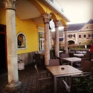 um restaurante ao ar livre com mesas, cadeiras e colunas em Zur goldenen Krone em Ehrenhausen