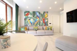 a living room with a white couch and a painting of birds at Parrots & Palms in Bordighera