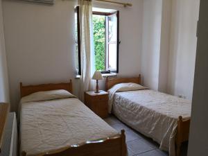 dwa łóżka w pokoju z oknem w obiekcie Spanos House w mieście Goudhi