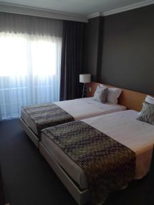 2 letti in una camera d'albergo con finestra di Dom Joao Hotel a Entroncamento