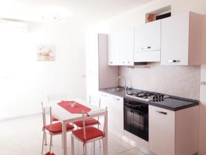 a kitchen with white cabinets and a table and chairs at Residence Maresol in Vieste