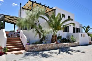 a white house with palm trees in front of it at Avra Milos in Zefiría