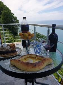 a table with a plate of pizza on a balcony at Albatross Kvariati Guest House in Kvariati