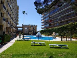 a swimming pool with two lounge chairs in the grass at Apartamento 315 en paseo marítimo 96 in Fuengirola