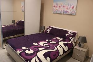 una camera con un letto con una coperta viola e bianca di Seaside Apartments a Marsaskala