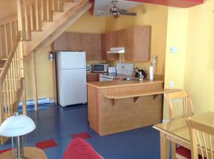 a kitchen with a white refrigerator and wooden cabinets at Chalets Multivoile 4 Saisons in Pointe-du-Lac +19 photos