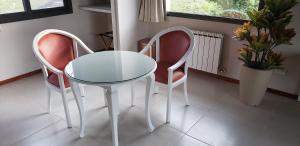 einen Glastisch und zwei Stühle in einem Zimmer in der Unterkunft Aires Serranos - Suites in La Cumbrecita