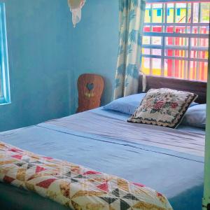 sypialnia z łóżkiem z poduszką i oknem w obiekcie Rainbow Beach Apartments & Rooms w mieście Calibishie