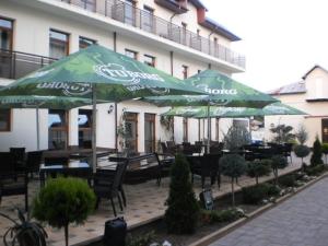 un patio avec des tables et des parasols en face d'un bâtiment dans l'établissement Hotel King, à Târgovişte