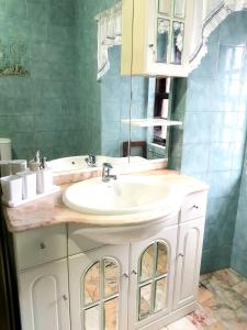 La salle de bains est pourvue d'un lavabo blanc et d'un miroir. dans l'établissement Apartamentos Garrett, à Horta