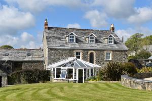 an old stone house with a greenhouse in the yard at Treveighan Farmhouse in Saint Teath