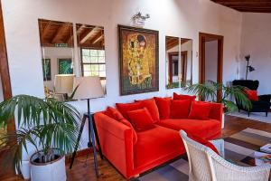 a living room with a red couch and a painting on the wall at Platanera Suites in Icod de los Vinos
