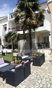 um pátio com sofás e uma palmeira em frente a um edifício em Villa Dolce Vita em Vodice