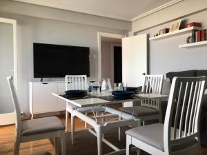 uma sala de jantar com uma mesa e cadeiras e uma televisão em VISTAS AL MAR em Santander