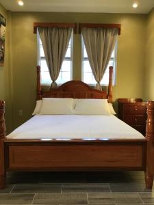 a bed with a wooden frame in a bedroom with a window at Hidden Treasure Vacation Home Bay Blue Suite 2 in Belize City