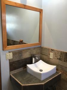 ein Badezimmer mit einem weißen Waschbecken und einem Spiegel in der Unterkunft Hidden Treasure Vacation Home Bay Blue Suite 2 in Belize City