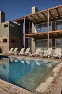 un grupo de sillas sentadas junto a una piscina en Villa Juana Bungalows & Suites, en Punta del Diablo