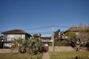 una casa con una pared de piedra y palmeras en Villa Juana Bungalows & Suites, en Punta del Diablo