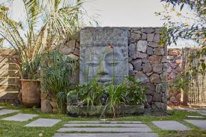 una estatua de una cara en una pared de piedra en Villa Juana Bungalows & Suites, en Punta del Diablo