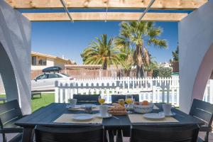 - une table sur une terrasse avec une clôture blanche et des palmiers dans l'établissement Villa Julia, à Riumar