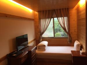 a room with a window and a bed with a television at New Life Hot Spring Resort in Yuli
