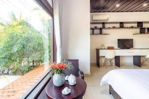 a bedroom with a bed and a window with a desk at Pearl Beach Homestay - Cua Dai Beach, Hoi An in Hoi An