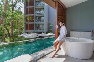 a woman in a bathing suit standing in front of a tub at The Nature Phuket - SHA Extra Plus in Patong Beach