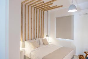 um quarto com uma cama branca e uma cabeceira em madeira em Joanna Villas em Kamari