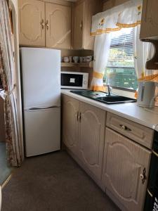 a kitchen with a white refrigerator and a window at 23 Glenfinart Caravan Park in Dunoon