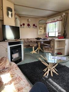 a living room with a fireplace and a glass table at 23 Glenfinart Caravan Park in Dunoon