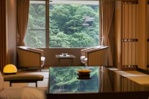 um quarto com uma mesa e uma grande janela em Arima Onsen Gekkoen Korokan em Kobe